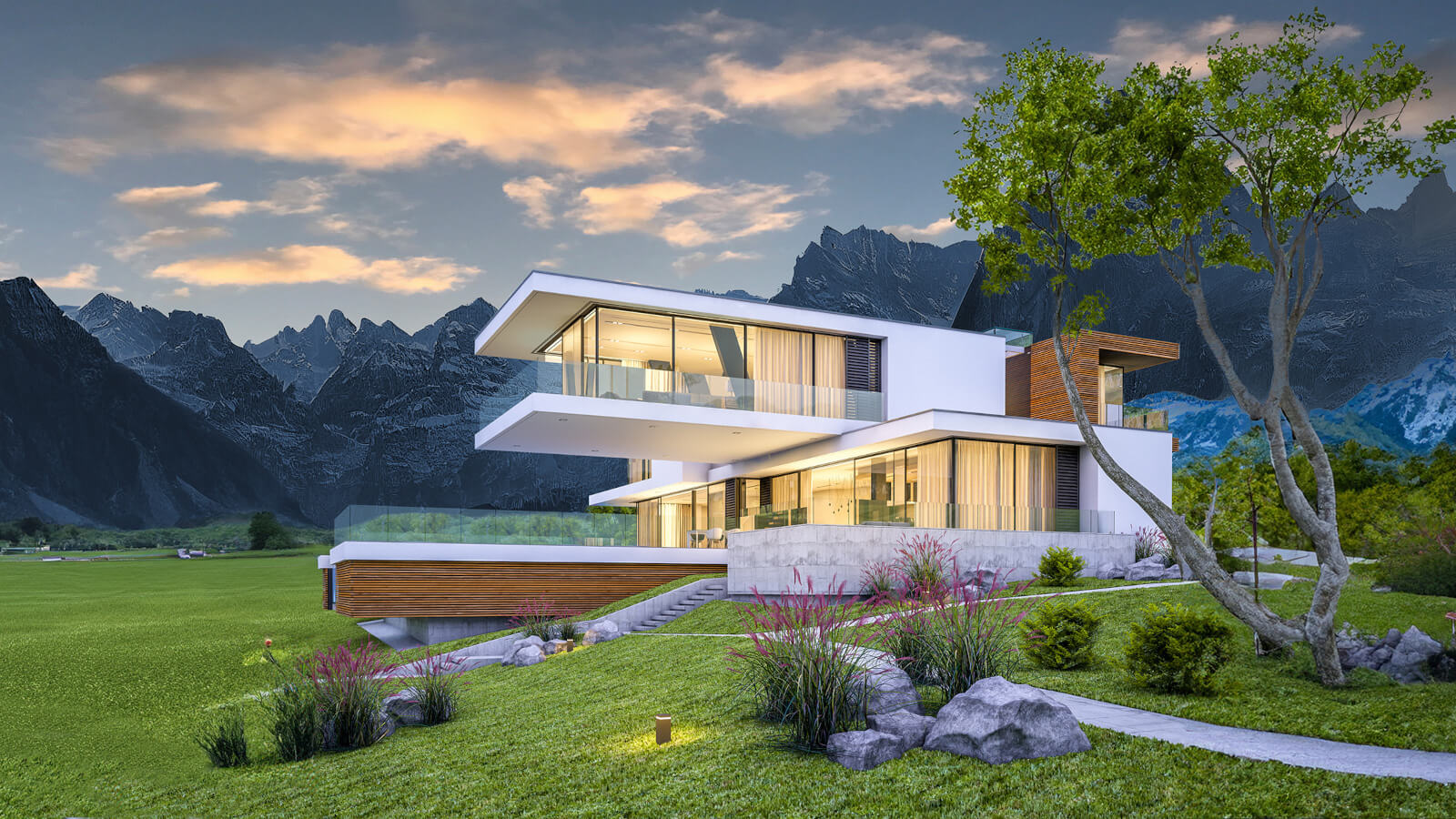 Ein modernes, mehrstöckiges Wohnhaus mit großen Glasflächen in einer grünen Landschaft vor einer Bergkulisse bei Abendlicht.