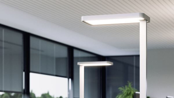 Das Bild zeigt zwei schlanke, moderne Stehleuchten in einem Büro, die für direkte und indirekte Beleuchtung sorgen und sich durch schlichtes Design und helle Lichtwirkung auszeichneen