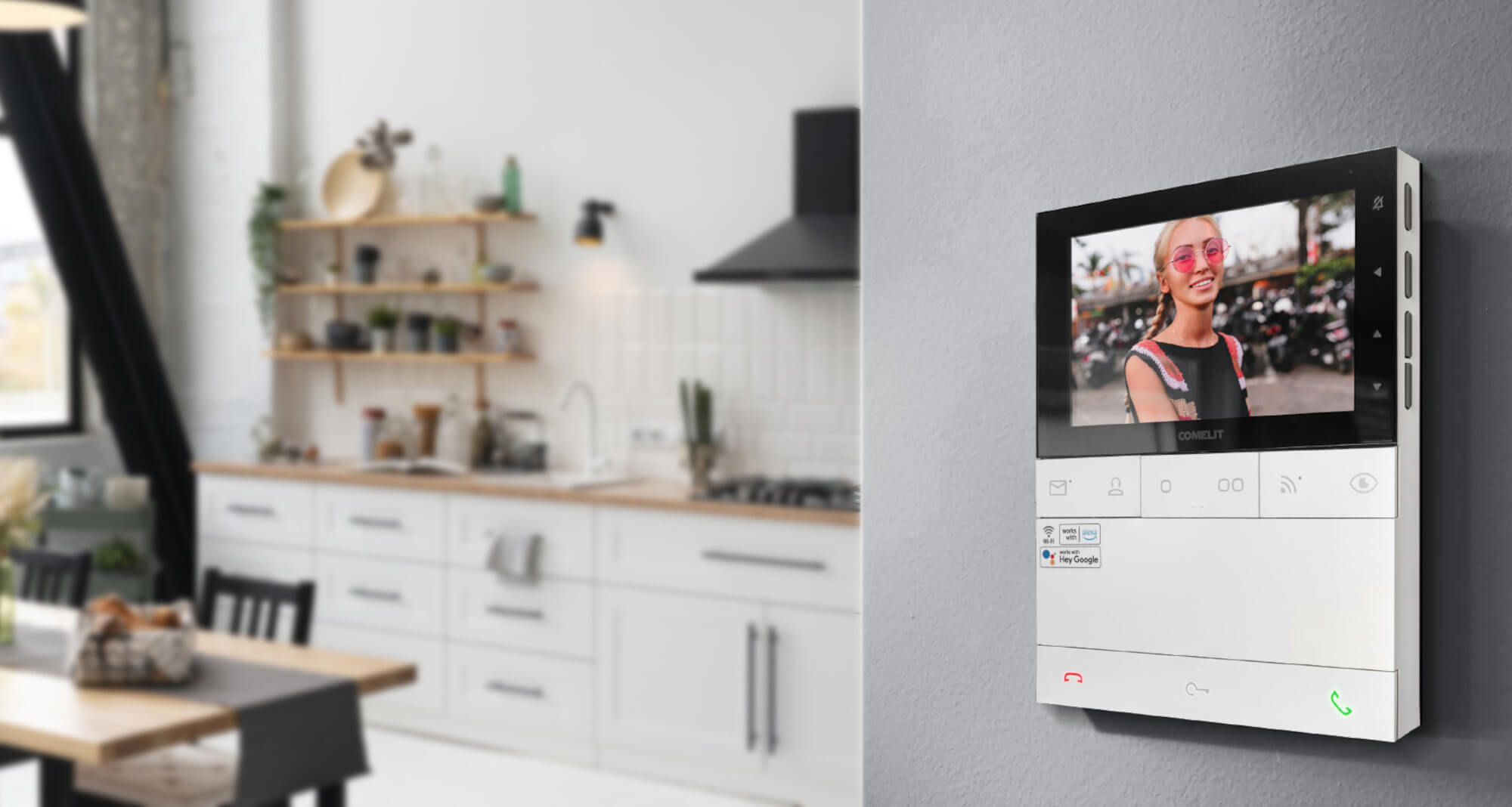 Das Bild zeigt eine moderne Wohnungsküche — an der Wand montiert ist eine Video-Gegensprechanlage mit Display; auf dem Bildschirm ist das Bild einer klingelnden Person zu sehen.
