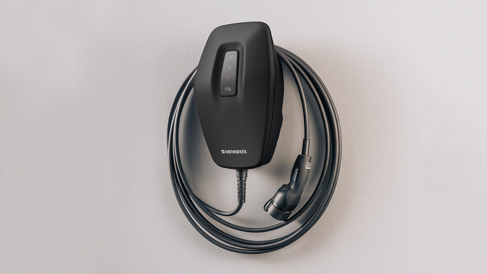 Das Bild zeigt eine schwarze Wallbox zum Laden eines Elektroautos, montiert an einer weißen Wand. Das Ladekabel ist ordentlich aufgewickelt, und der Stecker hängt seitlich daneben.