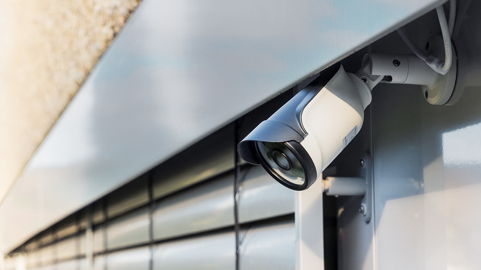Das Bild zeigt eine moderne Überwachungskamera, die an einer Gebäudewand montiert ist.