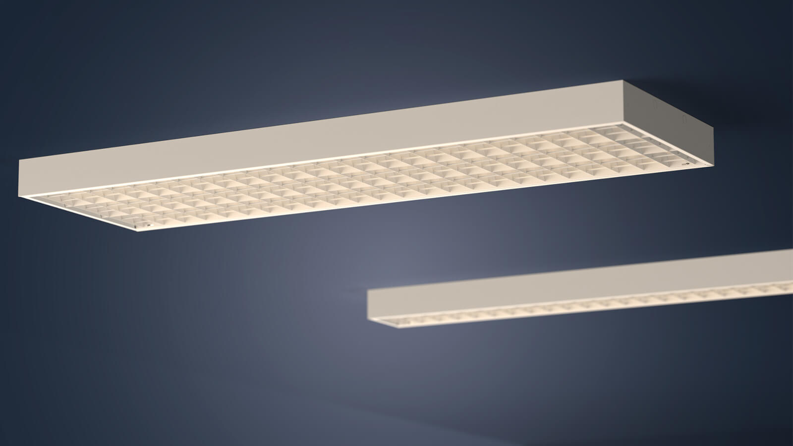 Das Bild zeigt zwei rechteckige Deckenleuchten mit Rasteroptik in unterschiedlicher Breite. Sie sind an einer dunkelblauen Decke montiert und leuchten in einem warmen Weißton.