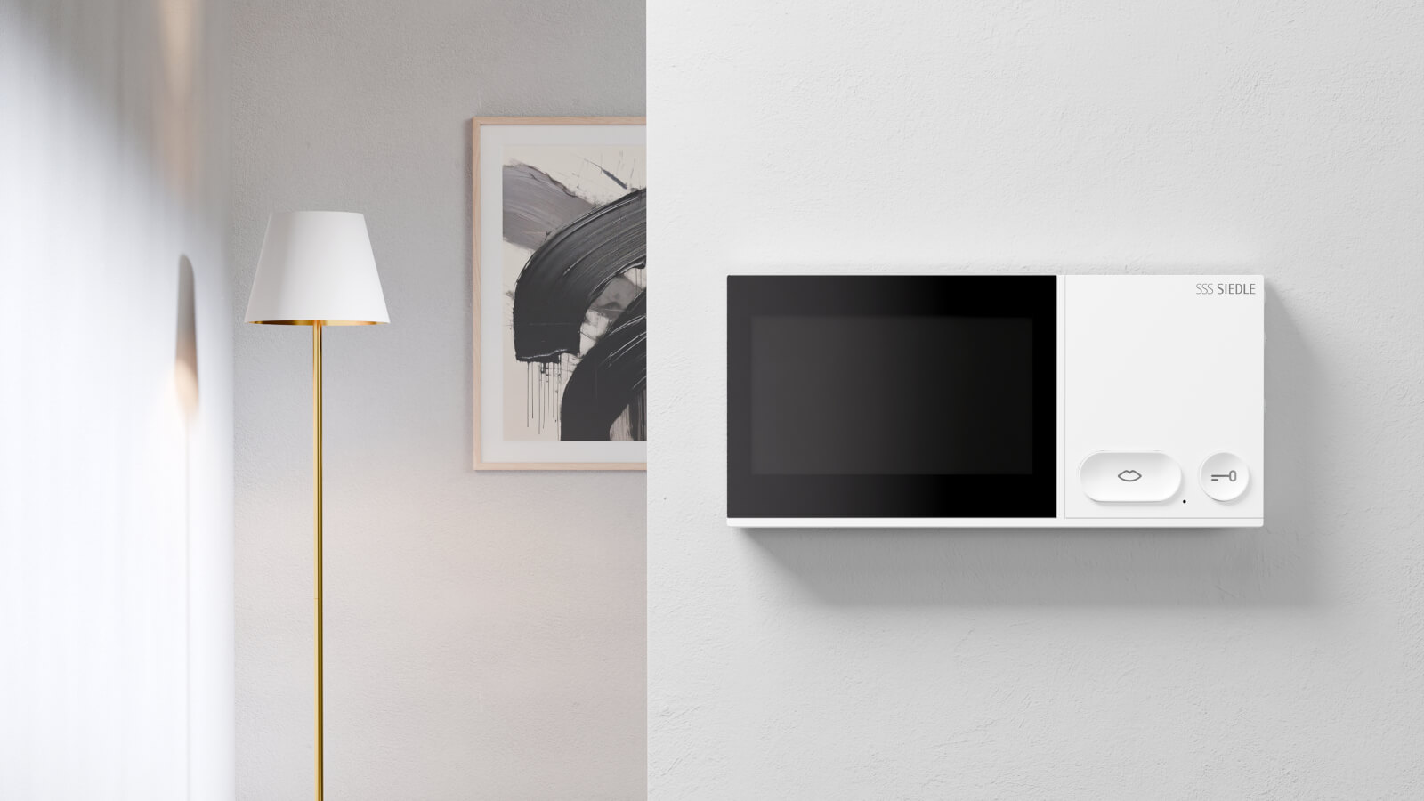 Das Bild zeigt auf der rechten Bildseite einen weiße Siedle IQ Innenstation an einer hellgrauen Wand. Auf der linken Bildseite sind eine goldene Stehleuchte mit weißem Schirm sowie ein Teil eines schwarzweißen Bildes zu sehen. 