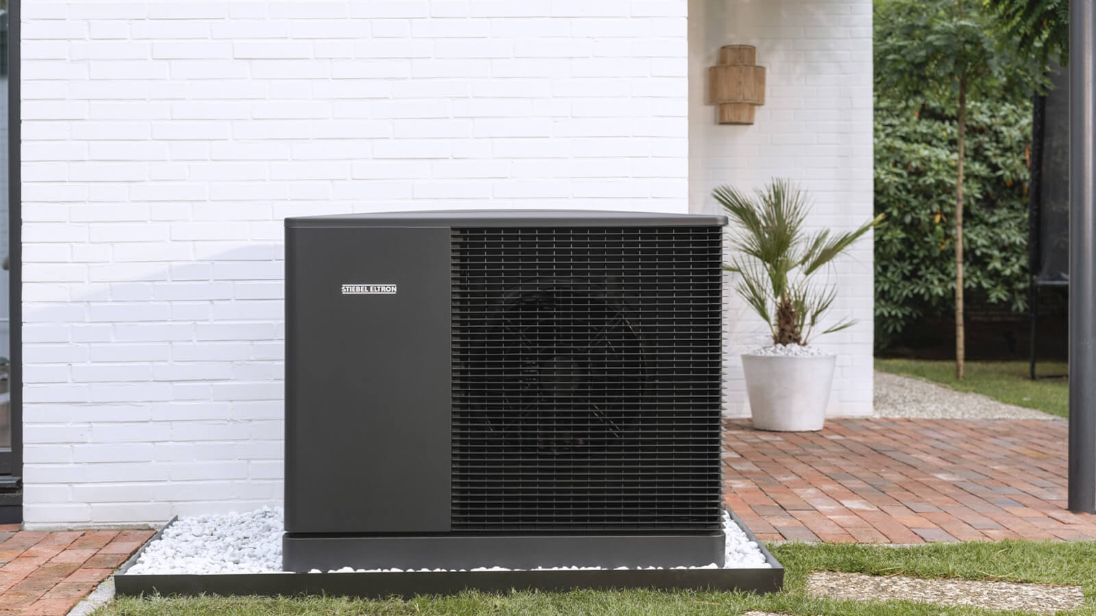 Das Bild zeigt eine moderne Wärmepumpe von Stiebel Eltron, die im Außenbereich vor einem weißen Haus aufgestellt ist.