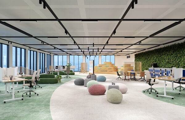 TRILUX YONOS – Your Next Office System Ein großzügig gestaltetes Büro mit offenen Arbeitsplätzen, farbigen Teppichzonen und Sitzgelegenheiten in Form von runden Hockern. An der rechten Wand befindet sich eine grüne Pflanzenwand. Die Decke ist mit einem linearen Leuchtensystem ausgestattet.