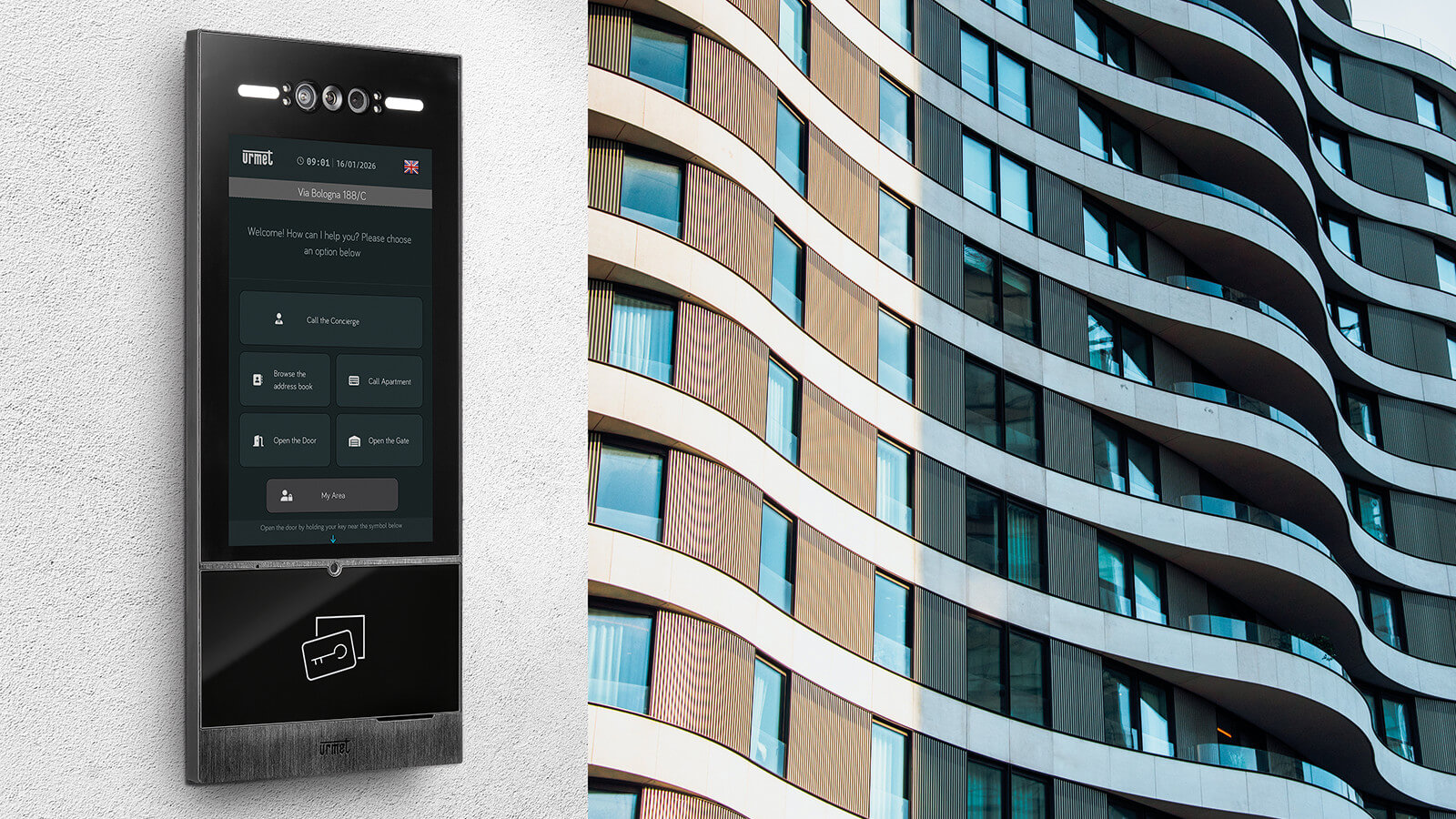 Moderne Türstation mit Touchdisplay an der Fassade eines mehrstöckigen Gebäudes mit geschwungener Architektur und großen Fensterflächen.