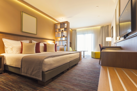 Das Bild zeigt ein stilvoll eingerichtetes Schlafzimmer in warmen Tönen. Das Bett steht links.