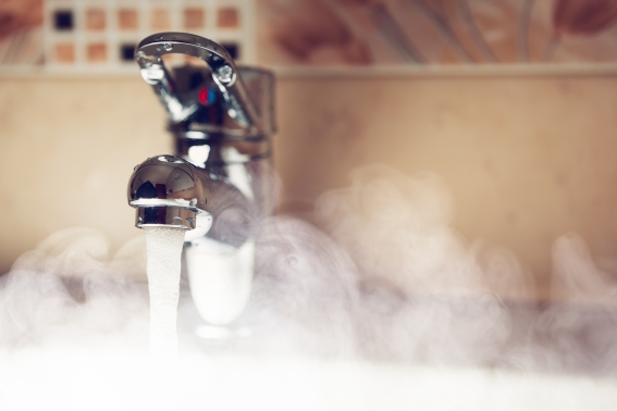 Dieses Bild zeigt heißes Wasser, wie es aus einer Leitung kommt und dampft.