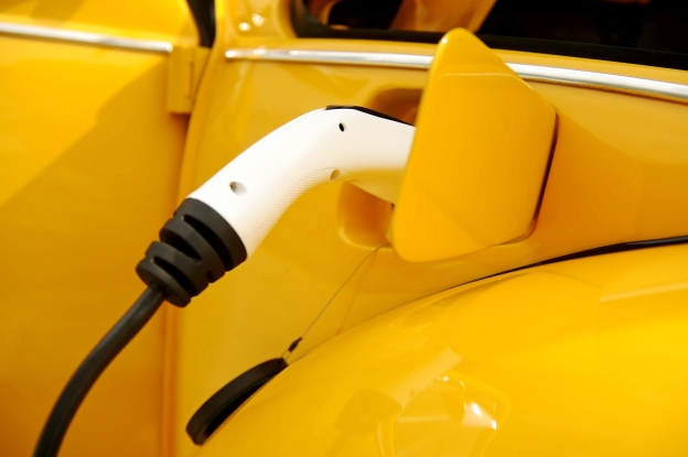 Das Bild zeigt ein gelbes E-Auto, welches gerade mit Strom betankt wird.