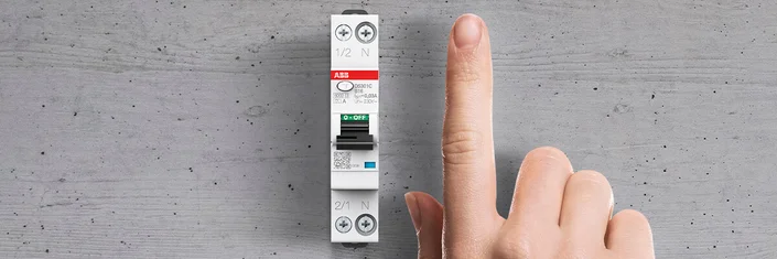 Das Bild zeigt einen ABB Schutzschalter und eine Hand mit ausgestrecktem Zeigefinger daneben.