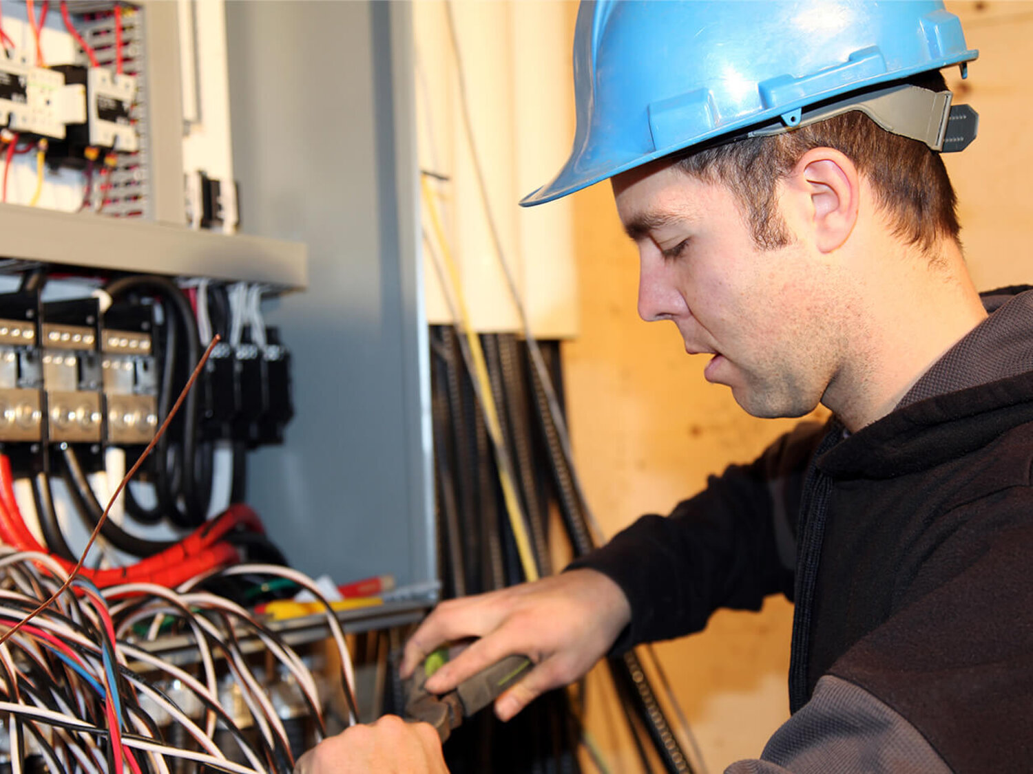 Dieses Bild zeigt einen Handwerker, der vor einem geöffneten Kabelschrank steht und an den Kabeln arbeitet.