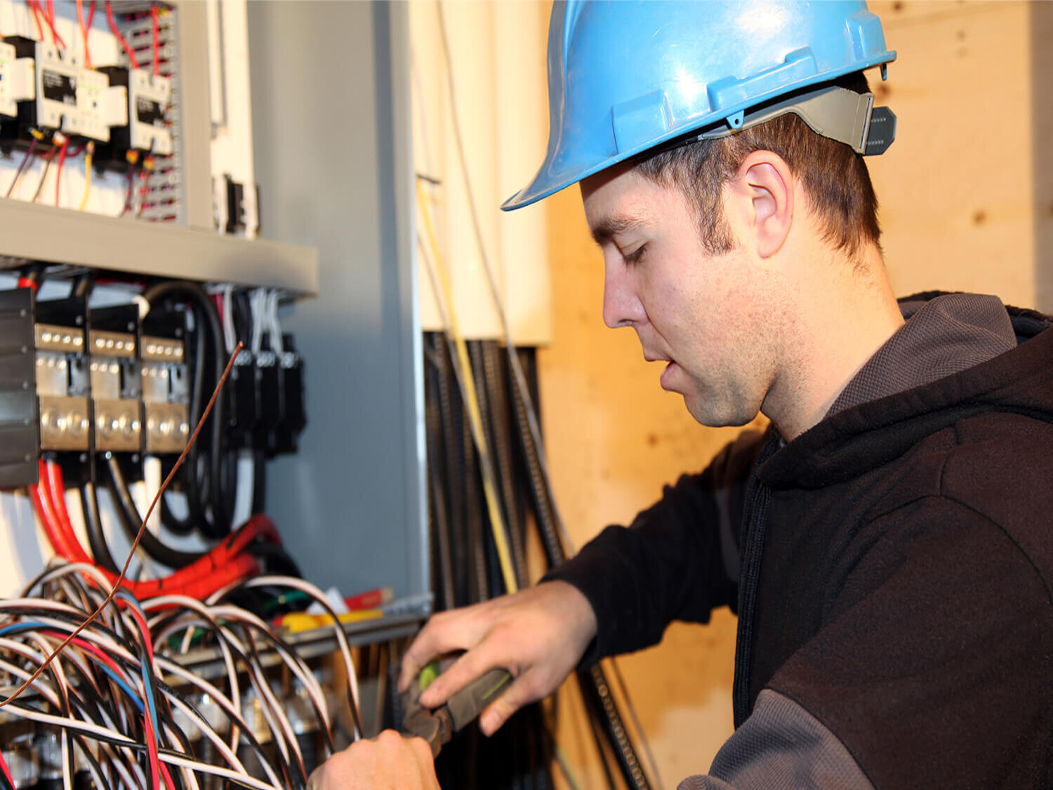 Dieses Bild zeigt einen Handwerker, der vor einem geöffneten Kabelschrank steht und an den Kabeln arbeitet.
