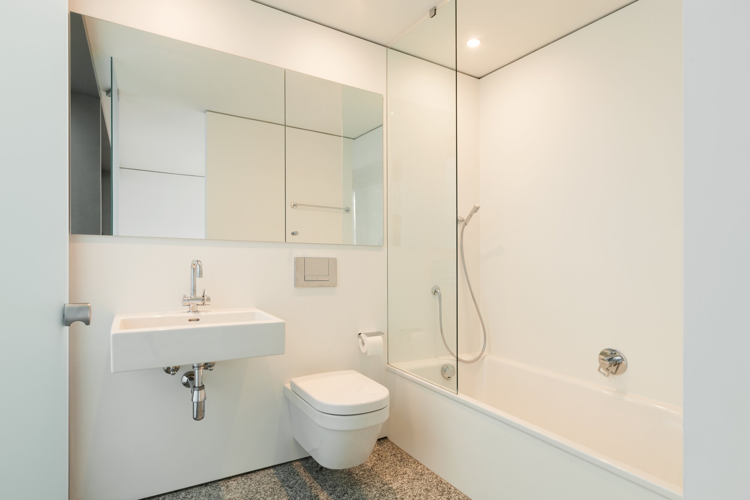 Dieses Bild zeigt ein modernes und funktionales Badezimmer, fast komplett in der Farbe weiß gehalten.