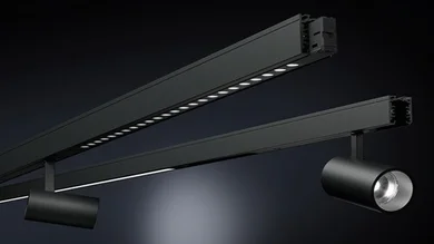 Das Bild zeigt ein schwarzes Schienensystem mit zwei unterschiedlichen LED-Leuchten. Eine Schiene ist mit einer durchgehenden, linienförmigen Lichtquelle ausgestattet, die andere mit zylinderförmigen Strahlern. Beide Elemente sind in einem schlichten, funktionalen Design gehalten. Der Hintergrund ist dunkel, wodurch die Leuchten klar erkennbar sind.