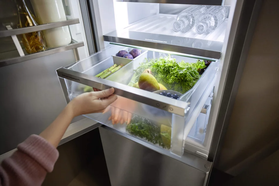 Person zieht ein Kühlfach mit frischem Obst und Gemüse aus dem Kühlschrank von Liebherr.