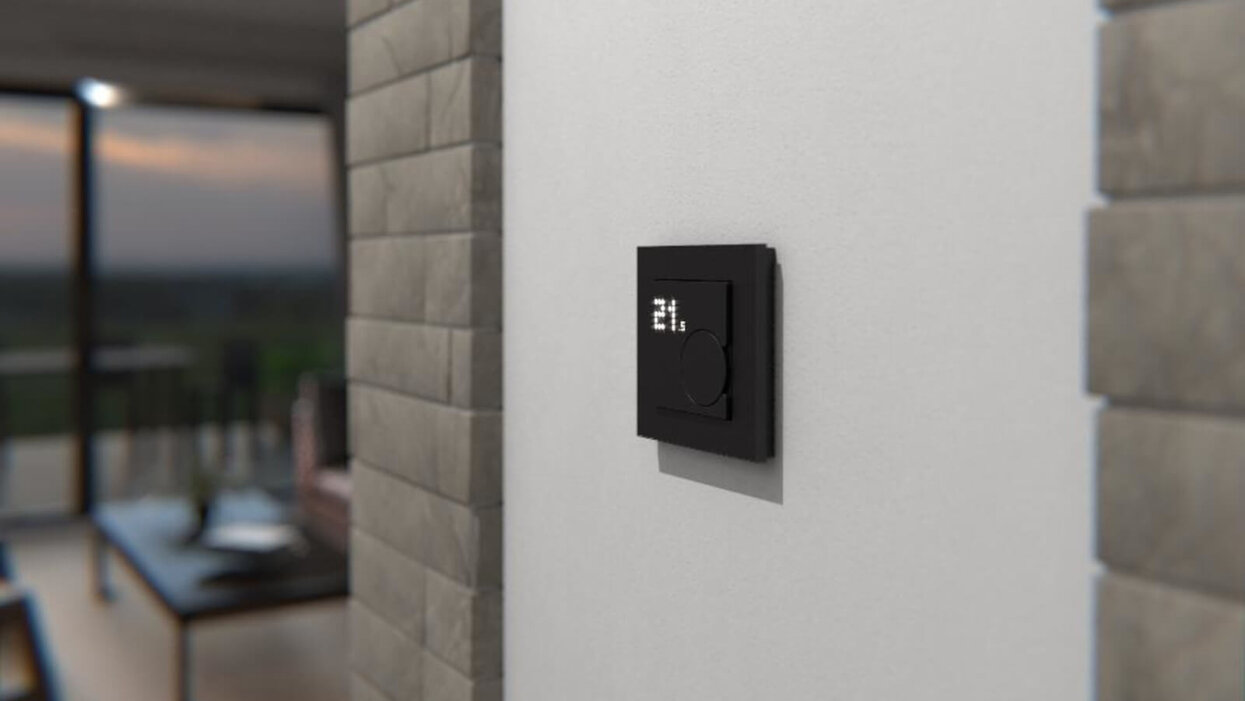 An der Wand eines Raumes befindet sich ein schwarzer Lichtschalter.