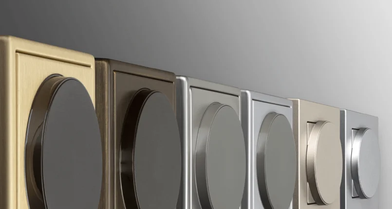 Das Bild zeigt mehrere moderne Drehschalter in verschiedenen Metallfarben, die nebeneinander an einer Wand angebracht sind.