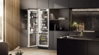 Einbaukühlschrank von Liebherr, der geöffnet ist und in eine elegante schwarzbraune Küchenzeile integriert wurde.