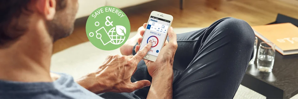 Dieses Bild zeigt eine Person von hinten auf dem Sofa sitzend, die gerade mit dem Smartphone etwas bedient.