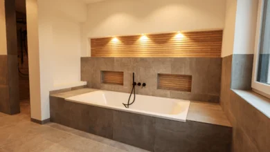 Das Bild zeigt eine moderne, weiße Badewanne mit Marmoreinfassung. Hinter der Badewanne ist eine große, mit Holz ausgekleidete Nische in der Wand eingelassen, die durch Downlights der Serie MULTISCREW beleuchtet wird.