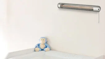 Über einem Wickeltisch ist ein Quarzheizer befestigt