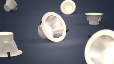 Mehrere runde, weiße Einbau-Downlights liegen und schweben vor einem dunkelblauen Hintergrund, eine Leuchte im Vordergrund strahlt warmes Licht ab.