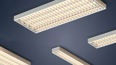Das Bild zeigt mehrere rechteckige Deckenleuchten mit Rasteroptik. Sie sind an einer dunkelblauen Decke montiert und leuchten in einem warmen Weißton.