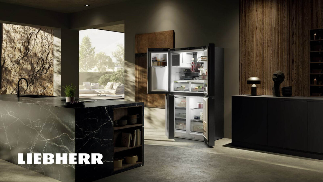 Das Bild zeigt eine elegante, dunkle Küche mit geöffnetem Liebherr-Kühlschrank, Naturmaterialien und einer warmen, wohnlichen Atmosphäre.