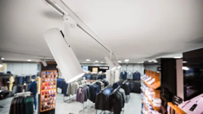 Das Bild zeigt die Nahaufnahme des Tracklights ZOOMtrack, das mit weiteren Tracklights an einer Schiene an der Decke eines Herrenbekleidungsgeschäftes befestigt ist.