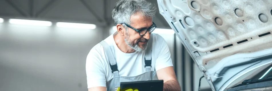 Person, die vor einem Fahrzeug steht, dessen Frontklappe geöffnet ist.