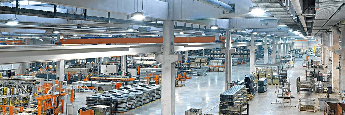 Produktionshalle hell erleuchtet mit Maschinen und Produktionsorten.