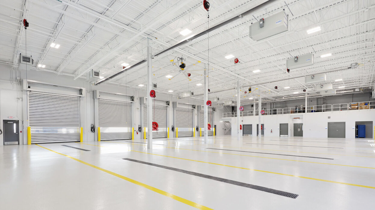 Rocks von Sylvania Helle, moderne Werkstatt oder Industriehalle mit weißen Wänden, großen Rolltoren und LED-Deckenleuchten.