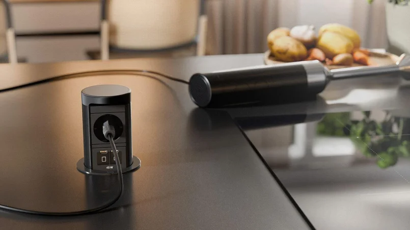 Ausfahrbares Anschlussmodul mit Steckdose und USB-Anschlüssen in einer Tischoberfläche.