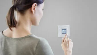Eine Person bedient einen smarten Thermostaten.
