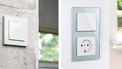 Bildmontage. Links ein Schalter in der Farbe Weiß an einer Wand. Rechts an einer Wand eine Schalter/Steckdosenkombination mit Glasrahmen.