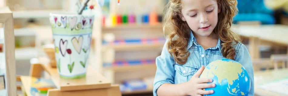 Das Bild zeigt ein kleines Mädchen, das einen Globus betrachtet.