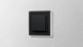 Schalter in der Farbe Schwarz des Herstellers Jung an der Wand montiert.