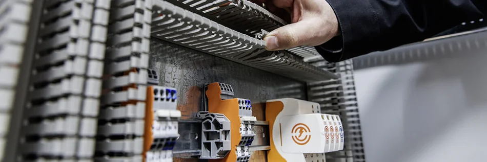 Ausschnitt aus einem Überspannungsschutz-System von OBO Bettermann und eine Hand, die auf etwas im System zeigt.