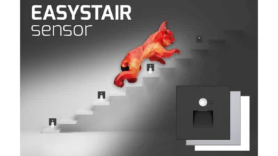 Im Vordergrund des Bildes sind in der rechten unteren Bild-Ecke drei Leuchten der Serie EASYSTAIRsensor in den Farben schwarz, weiß und grau abgebildet. In der linken oberen Bild-Ecke steht zweizeilig der Schriftzug EASYSTAIR sensor. Der Hintergrund zeigt eine weiße Treppe mit regelmäßig angebrachten Stufenleuchten. Ein grafisch dargestellter roter Luchs, Markenbotschafter des Herstellers Dotlux, läuft die Treppe hinauf. Die Stufenleuchten, die er bereits passiert hat, strahlen nach unten ab. Die restlichen Stufenleuchten sind dunkel.