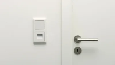 Das Bild zeigt den Rahmen eines 2-fach-Wandschalters mit Lichtschalter und Leuchte EASYGUIDE von Dotlux neben dem Türgriff einer weißen Tür.