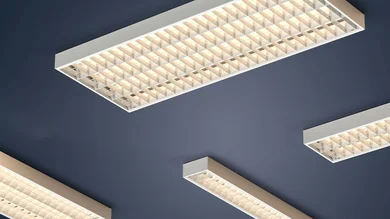Das Bild zeigt mehrere rechteckige Deckenleuchten mit Rasteroptik. Sie sind an einer dunkelblauen Decke montiert und leuchten in einem warmen Weißton.