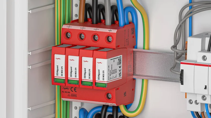 Das Bild zeigt eine rote Mehrfach-Überspannungsschutzklemme in einem Schaltschrank, mit farbigen Leitungen und mehreren angeschlossenen Modulen.