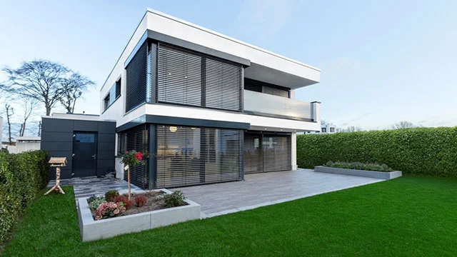Modernes Wohnhaus mit großen Fenstern und Rademacher Sicht- und Sonnenschutz im Grünen.