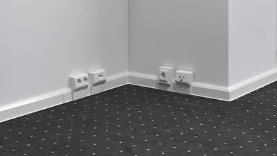 Helle Sockelleiste am Boden, davor ein dunkelgrauer Teppich als Bodenbelag.