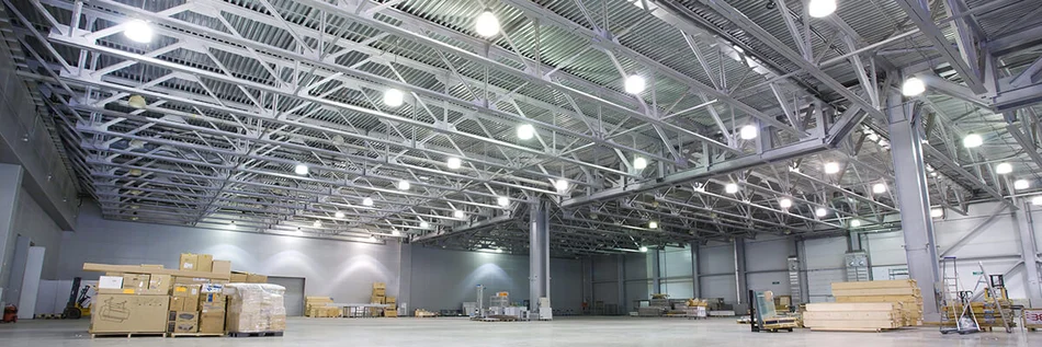 Das Bild zeigt eine moderne Lagerhalle, die durch viele BRUMBERG LED-Hallentiefstrahler SOL Highbay ausgeleuchtet wird..