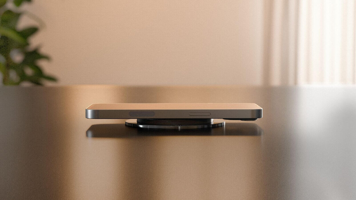 Smartphone auf integrierter Qi2-Ladefläche in einer Tischoberfläche.