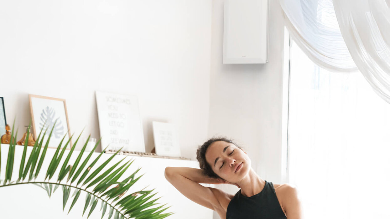 Eine Frau entspannt sich in einem hellen, modern eingerichteten Raum mit Pflanzen und dekorativen Bildern.