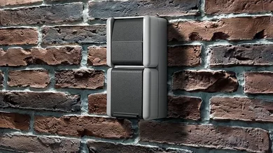 Zu sehen ist ein zwei­teiliger grauer Wandschalter auf einer Backsteinwand. Das Design wirkt robust und schlicht, passend für den Außen- oder Industrieeinsatz.