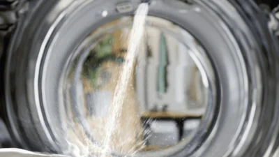Blick aus der Waschmaschine heraus durch das Glas der Waschmaschine. Im Hintergrund ist schemenhaft ein Raum zu sehen.