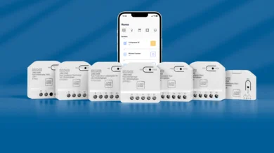 Eine Reihe kompakter Smart-Home-Module ist vor blauem Hintergrund angeordnet, dahinter ein Smartphone mit geöffneter Steuerungs-App.